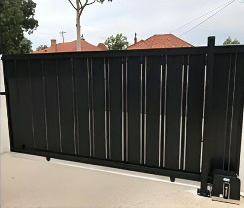 Black vertical slat sliding gate with a sliding gate motor at the end of the track