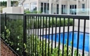 Black flat-top aluminium pool fence around an in-ground pool