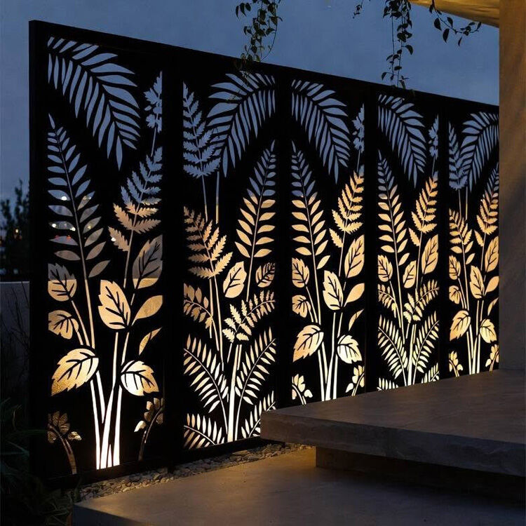 Three fern pattern laser-cut screens lit from behind at night